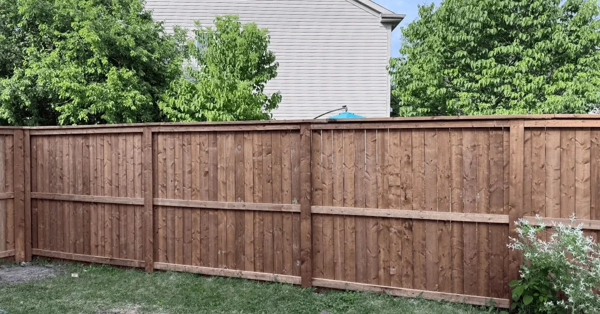 Six-foot solid wood privacy fence with vertical boards in a suburban backyard